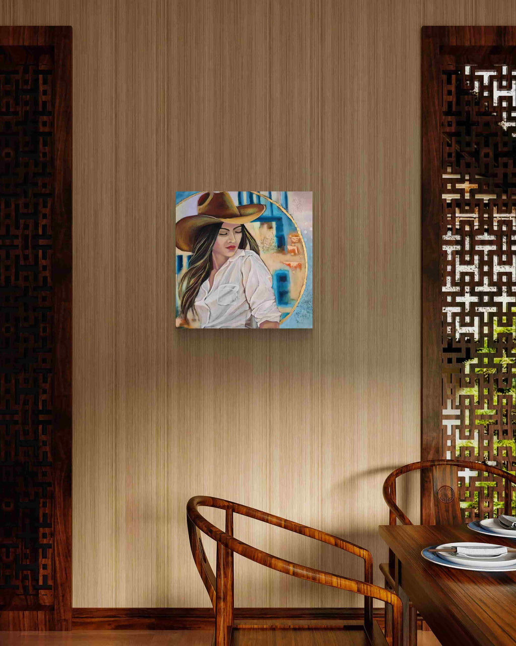 Mixed media painting of a woman wearing a cowboy hat on a wooden wall above a table with chairs.