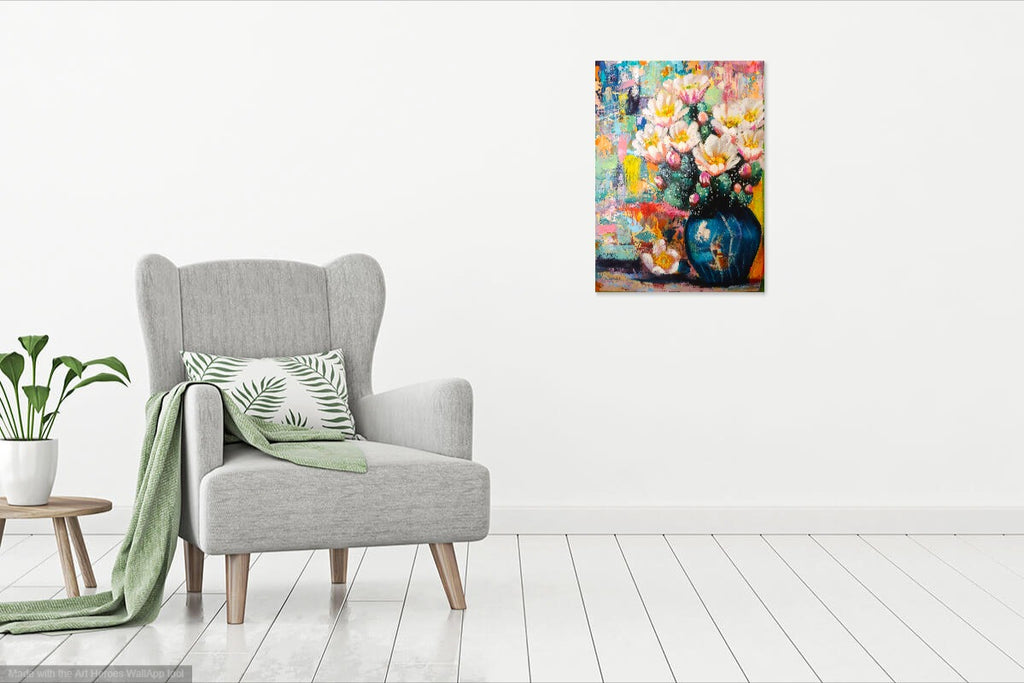 Gray armchair with a green blanket and pillow in a room with a colorful floral painting on the wall.