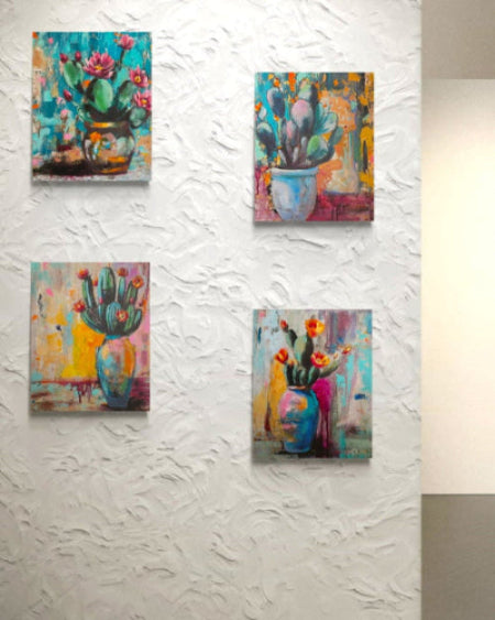 Set of four colorful cactus paintings on a textured white wall.