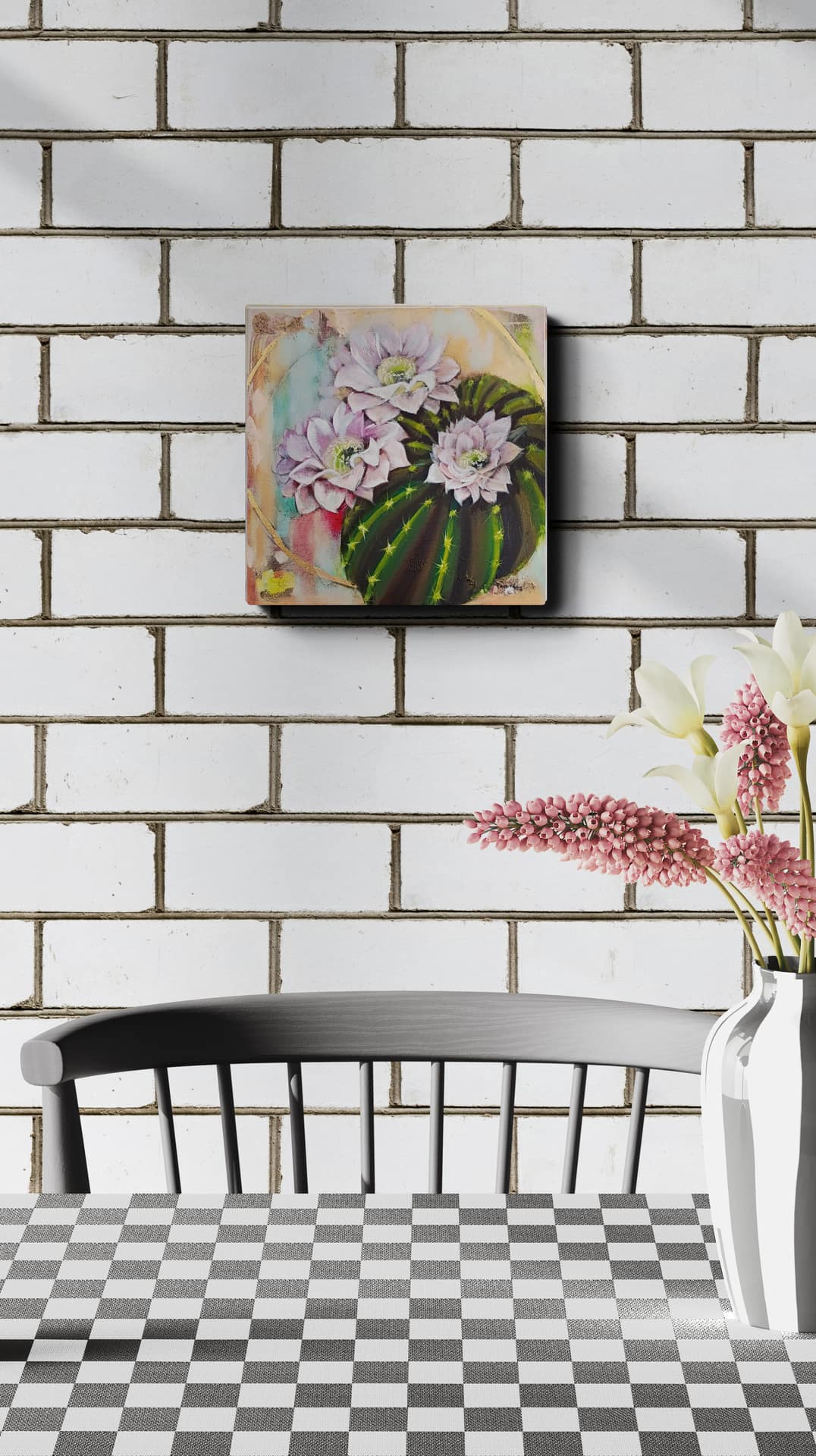 Decorative wall art with flowers on a white brick wall above a black chair and checkered table.