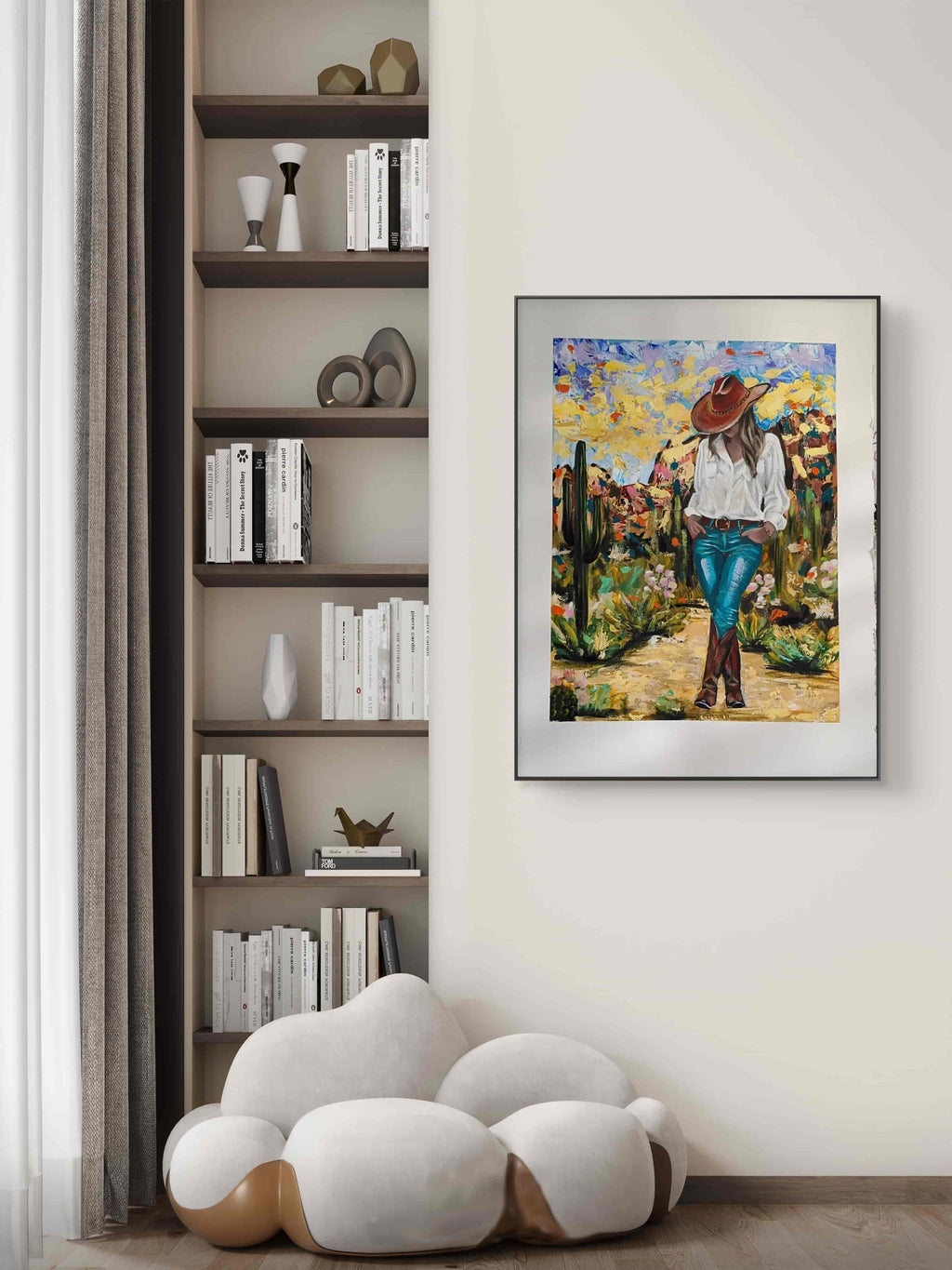 Framed artwork of a person in a desert landscape on a wall next to a bookshelf.