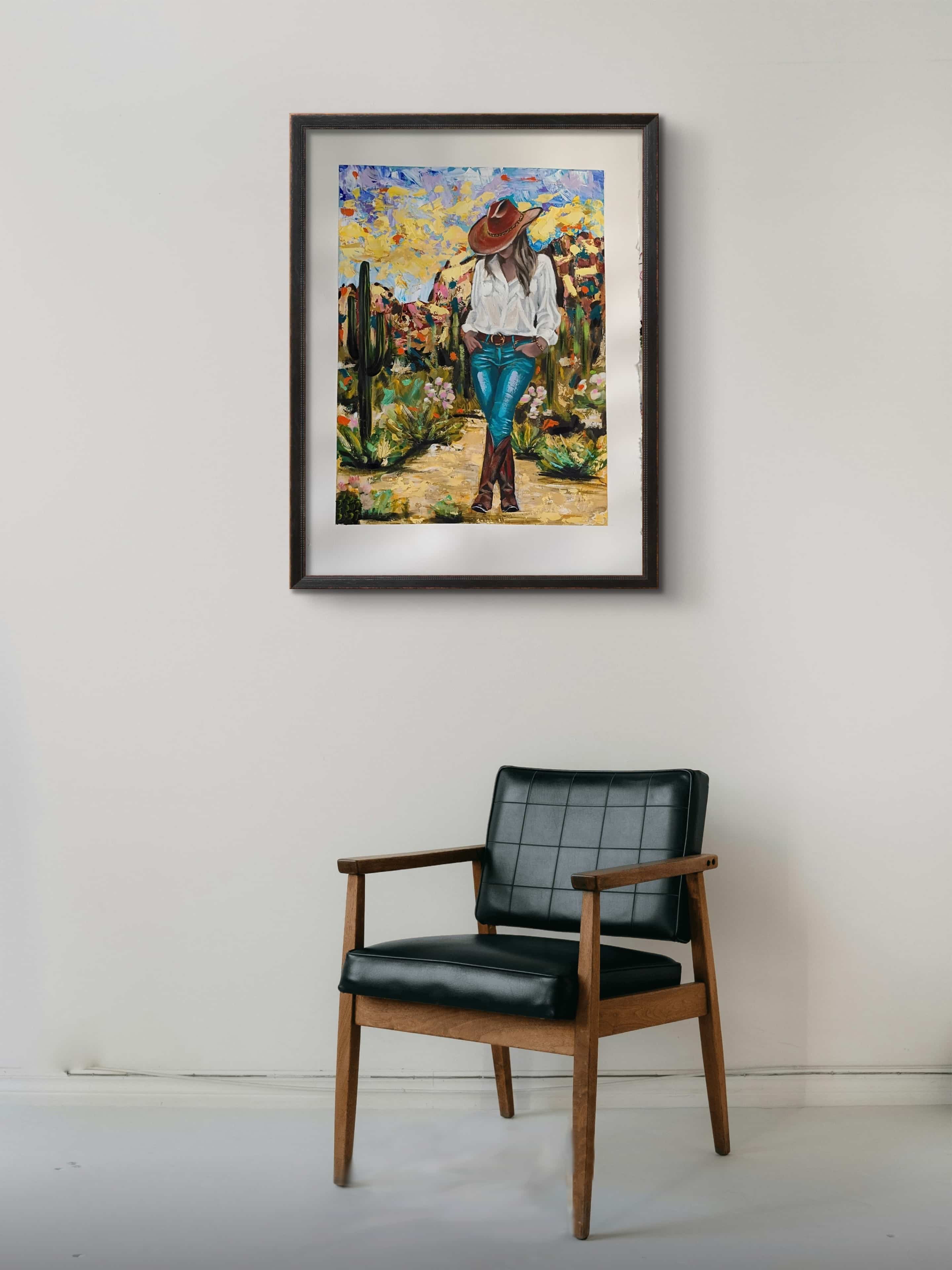Framed painting of a person in a desert landscape above a black chair.